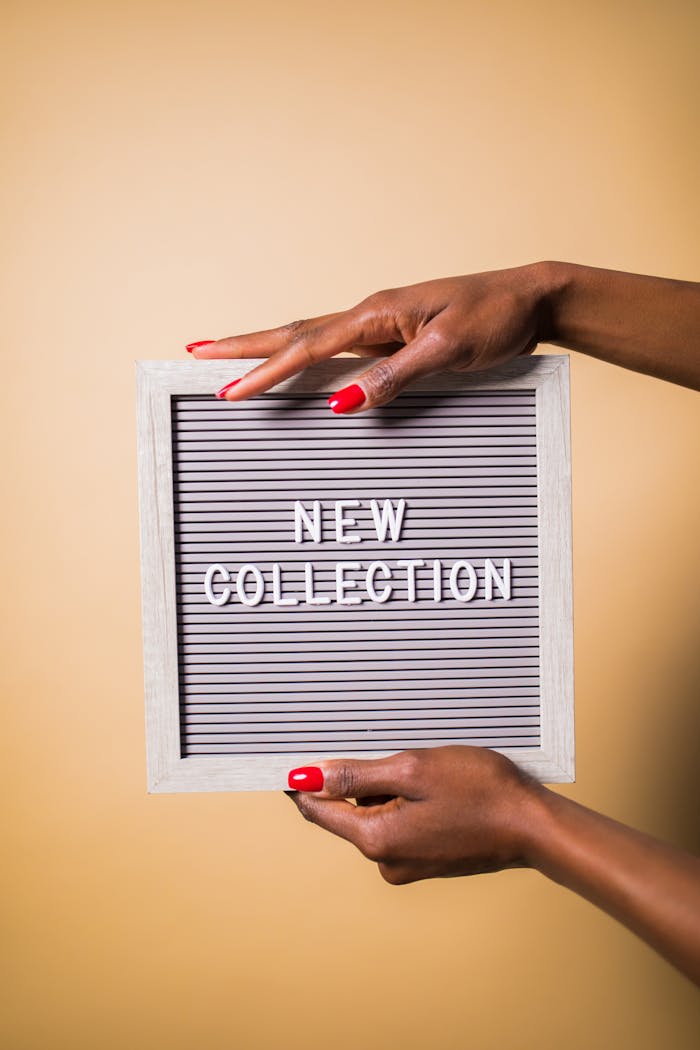 Stylish hands presenting a modern sign board with 'New Collection' text.