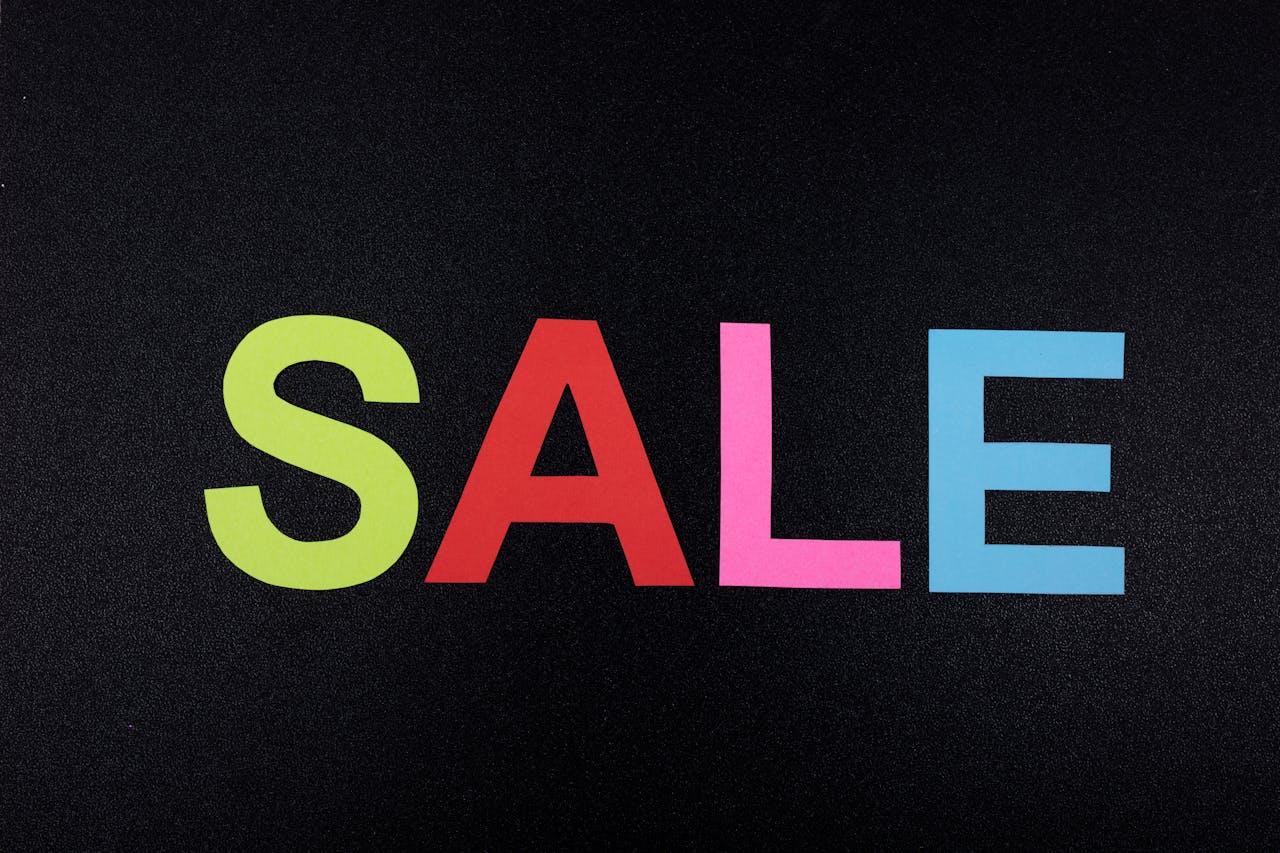 Multicolor letters spelling SALE on a textured black surface, perfect for promotional use.